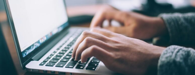 Close view of a job seeker working on their cover letter at their laptop.
