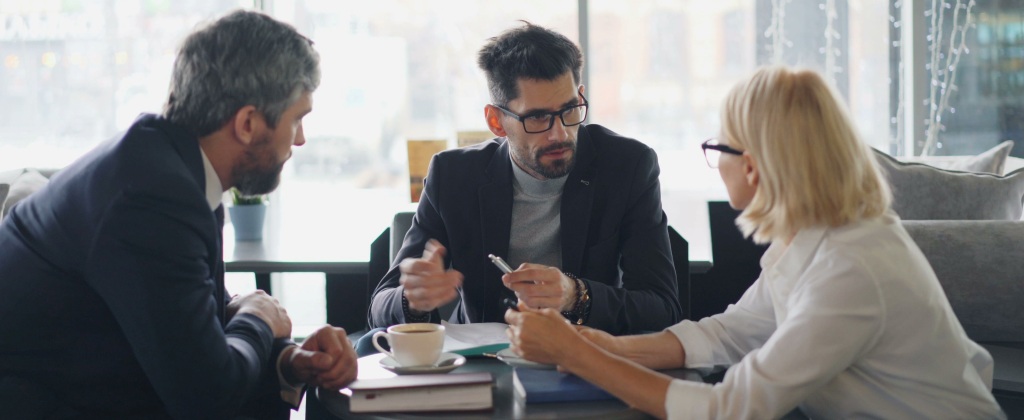 Trio of coworkers talking and bonding in the office while ignoring remote colleagues.