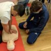 Two students in a CPR instructor class performing CPR on a mannequin