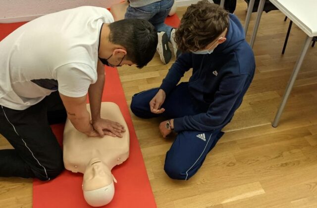 Two students in a CPR instructor class performing CPR on a mannequin