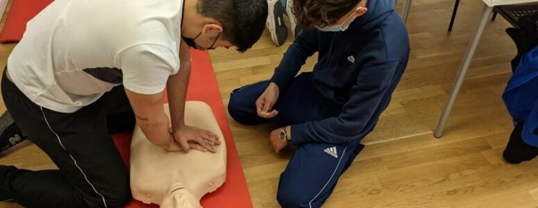 Two students in a CPR instructor class performing CPR on a mannequin