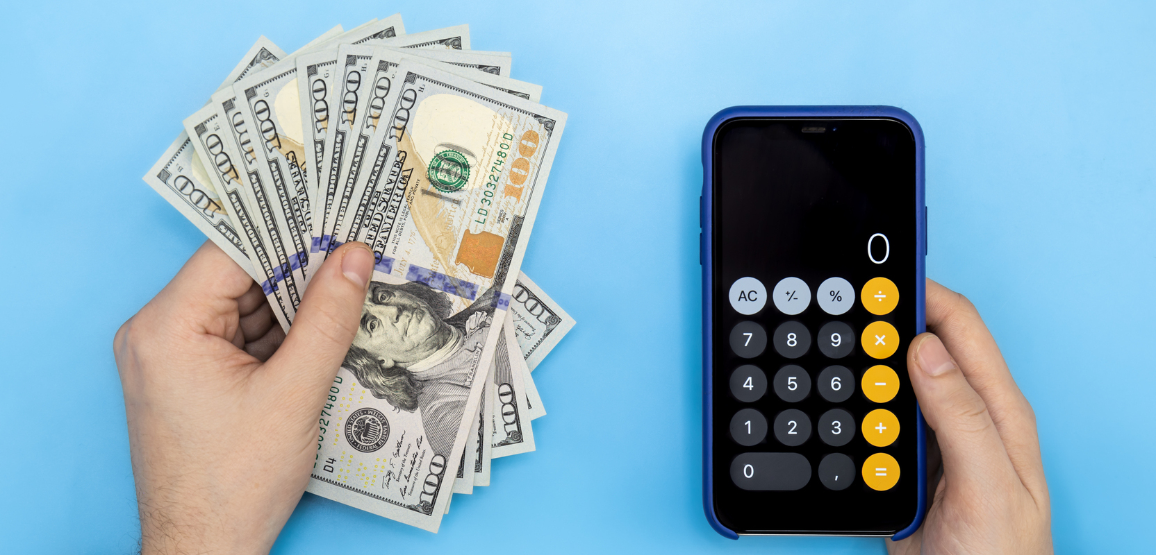 Money and a calculator in a smartphone in male hands on a blue background, top view