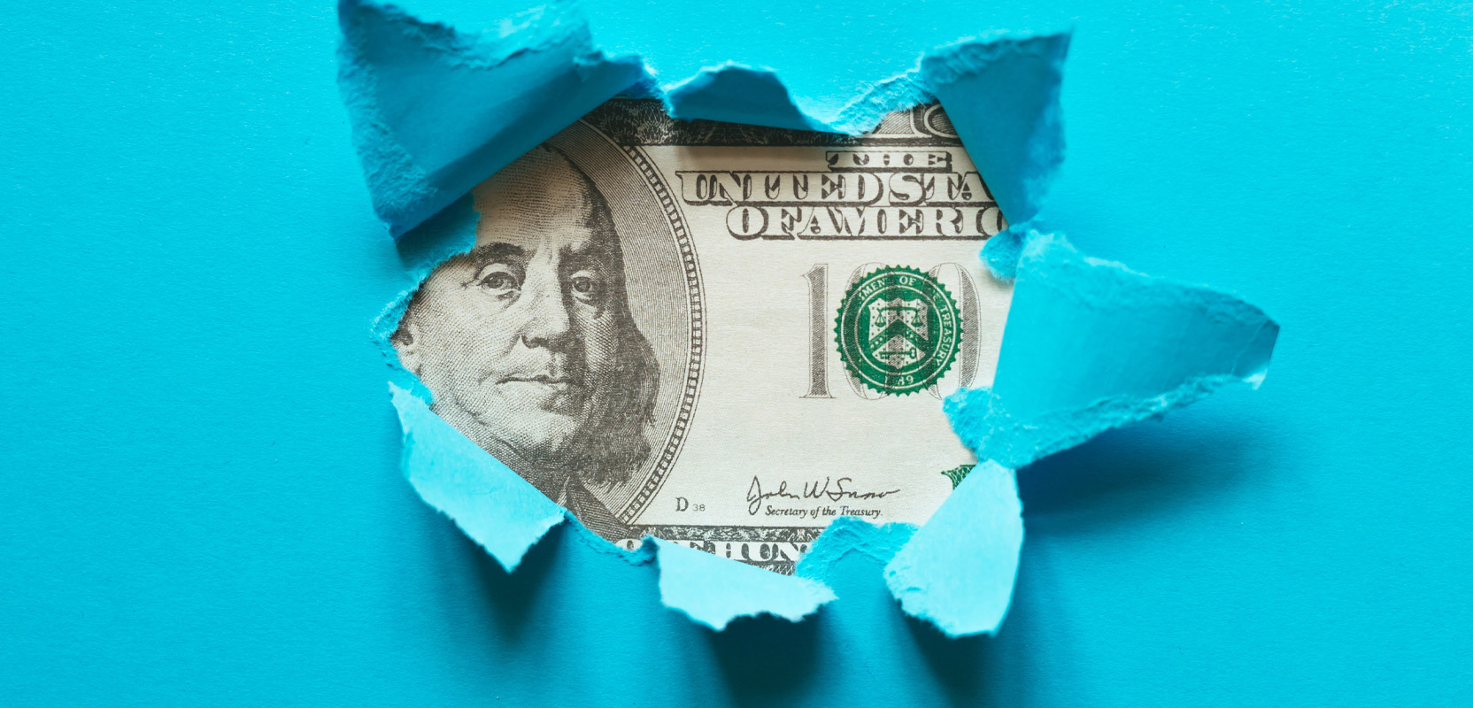 Blue paper being ripped open to show a hundred-dollar bill