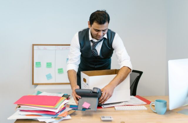 A smiling employee packing up their desk after revenge quitting.
