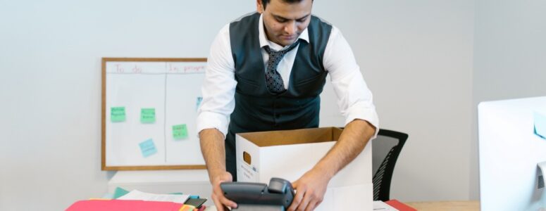 A smiling employee packing up their desk after revenge quitting.