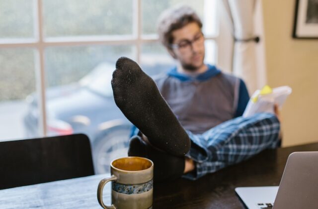 Remote worker reading with his feet on his desk during working hours.