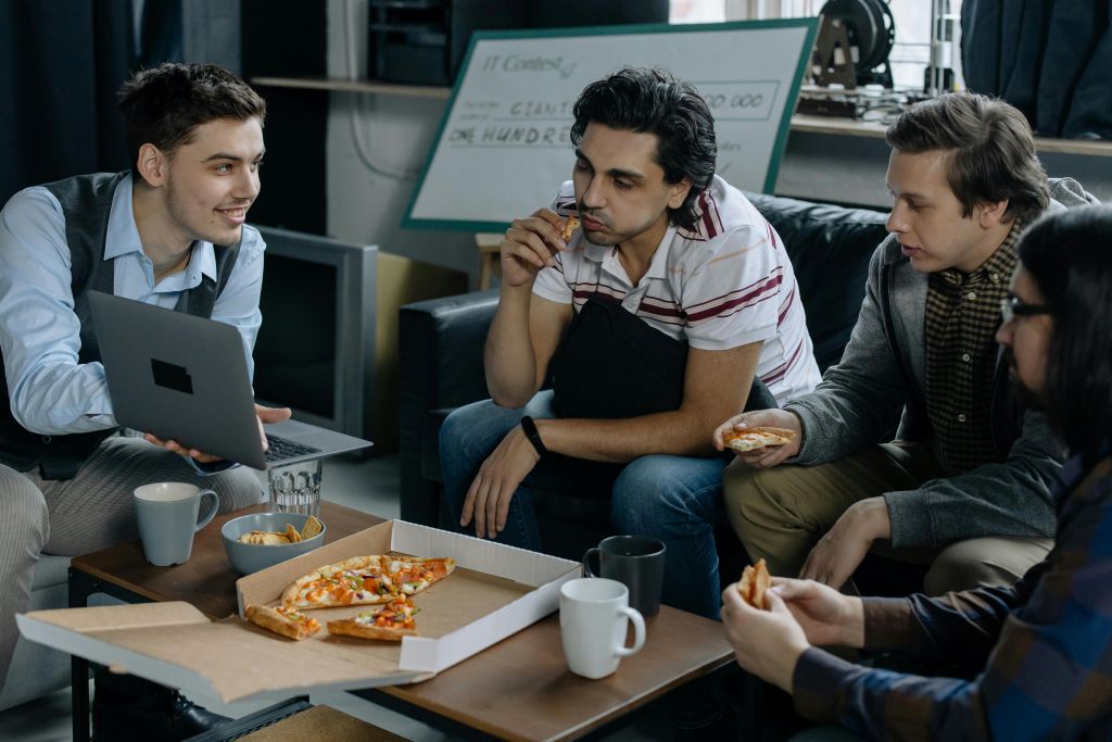 Employees sitting and eating pizza in their break room.