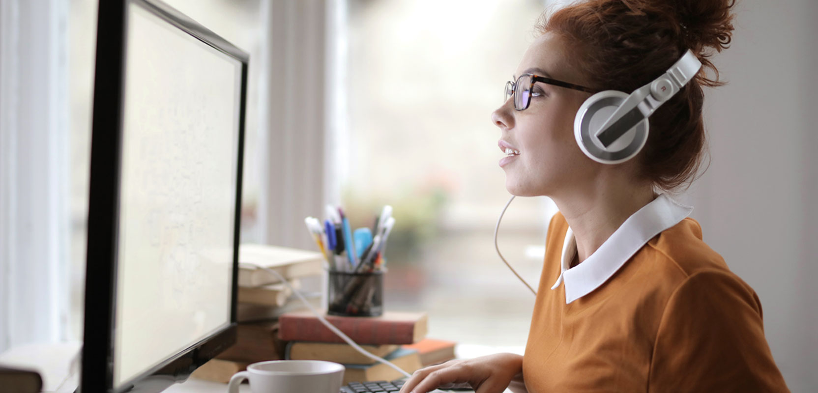 Freelance transcriptionist working at her computer and wearing headphones