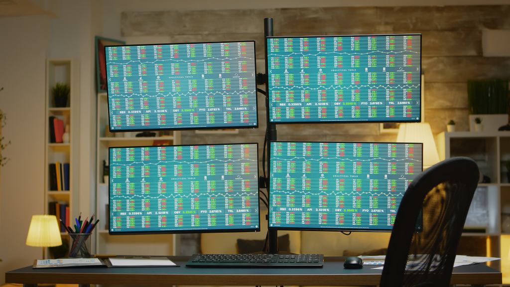 Empty chair by screens with financial stock market data.