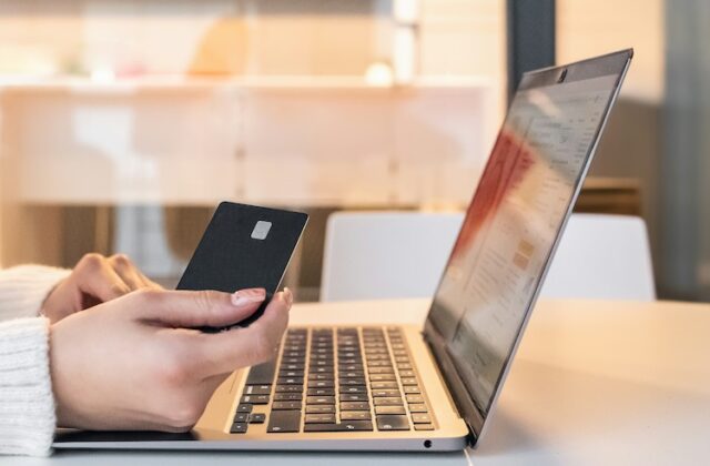 Woman sitting at her laptop with her phone using Fetch to save money.