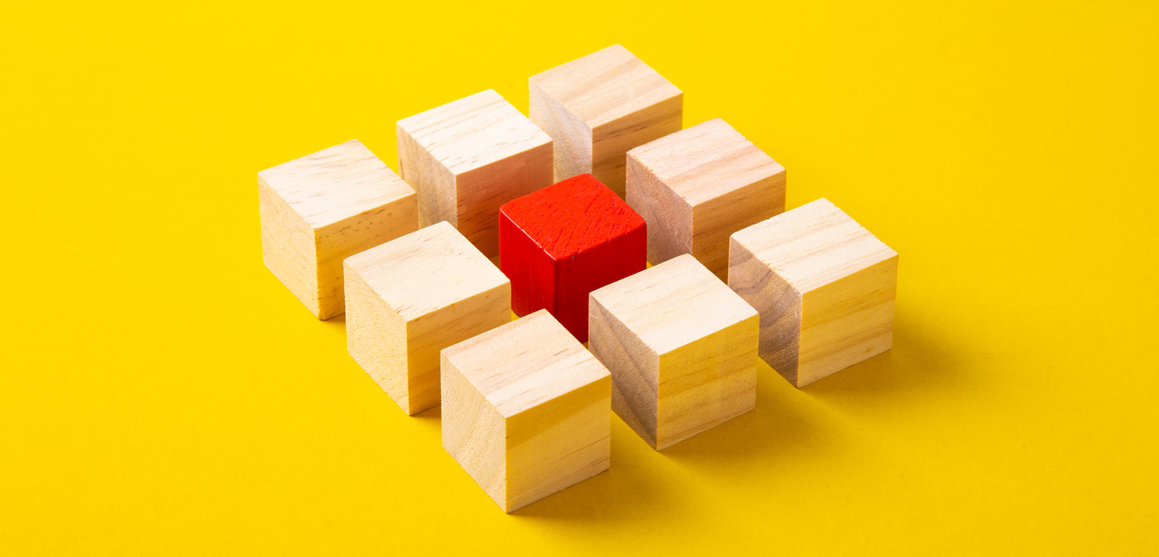 Square of nine wooden blocks with a red block in the center, symbolizing a profitable niche for a freelance blog