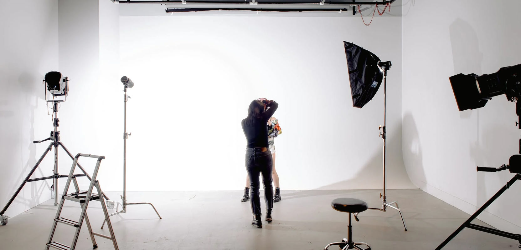 Photographer taking a picture of someone in a professionally lit studio for their freelance photography side hustle