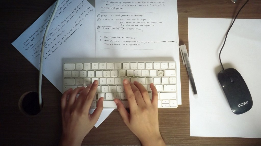 Freelance referring to handwritten notes when typing up a blog post.