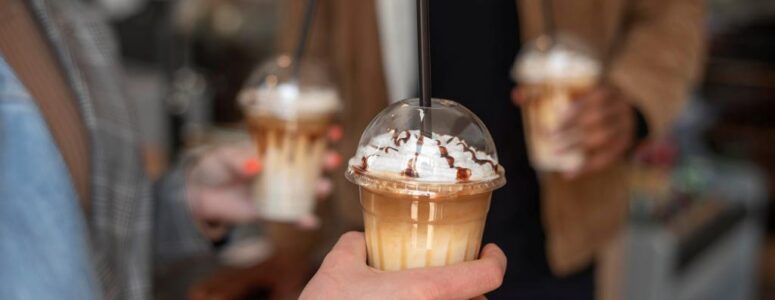 Close view of a man holding a fancy coffee drink.
