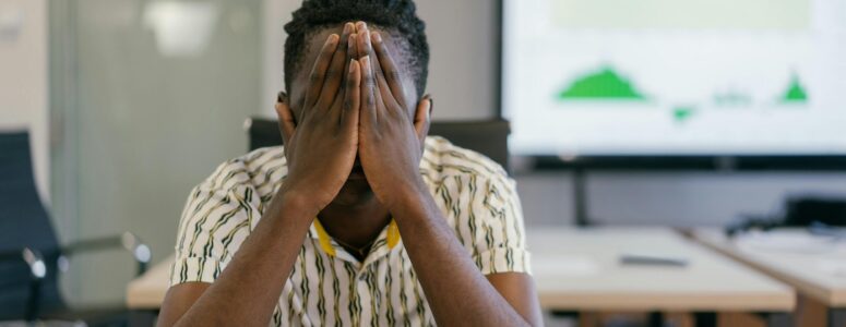Frustrated employee with his hands over his face.