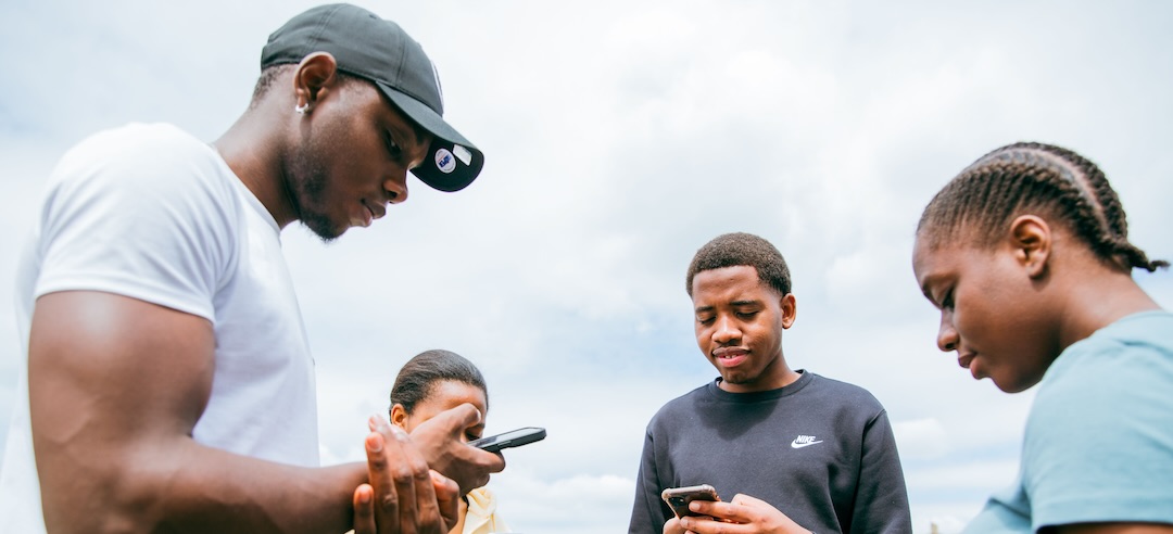 Group of young friends looking at their phones.
