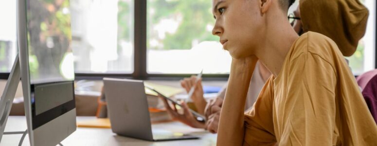 Younger office worker looking bored while working on computer.