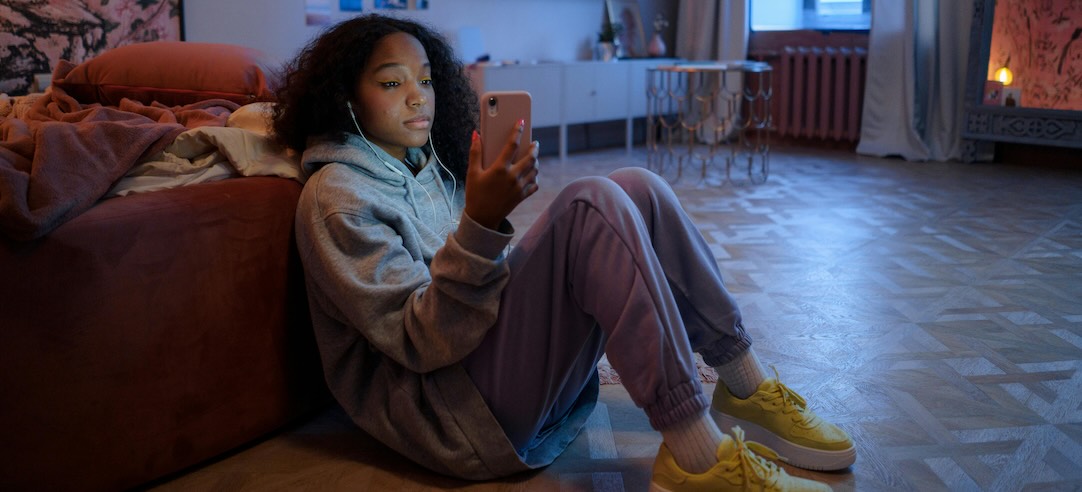 A teenager alone in her room, looking at her phone.