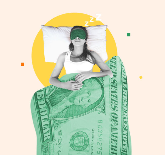 Woman lying in bed under a dollar-patterned blanket representing getting paid to sleep as a side hustle
