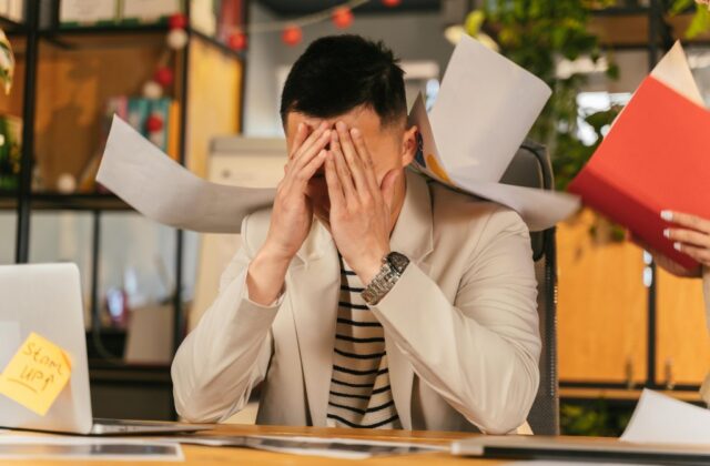 A stressed worker overwhelmed with paperwork after a ghost promotion.
