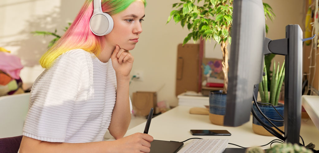 Designer listening to music through headphones and working at her computer