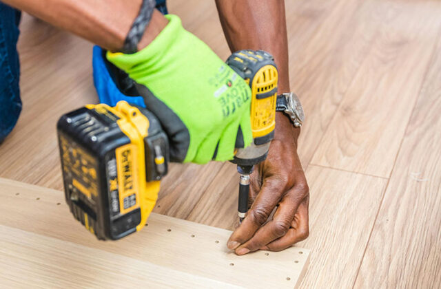 Close view of a handyman holding a drill as they complete a small task for their side hustle.