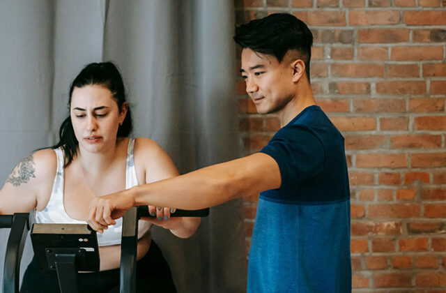 Professional health coach giving fitness advice to a client on an elliptical