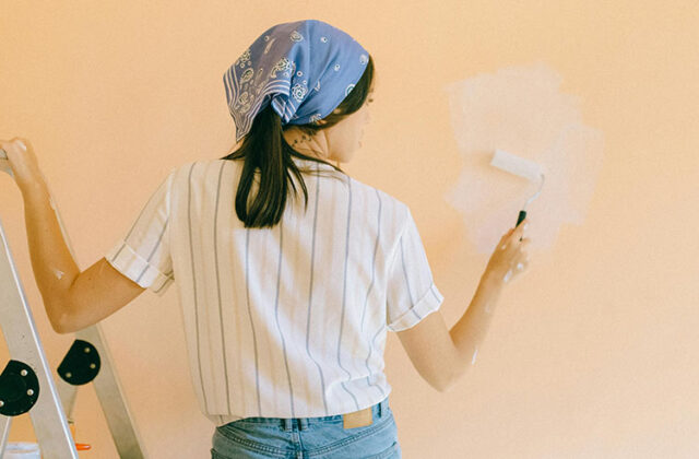 Professional house painter using a paint roller and white paint to paint a wall inside a house