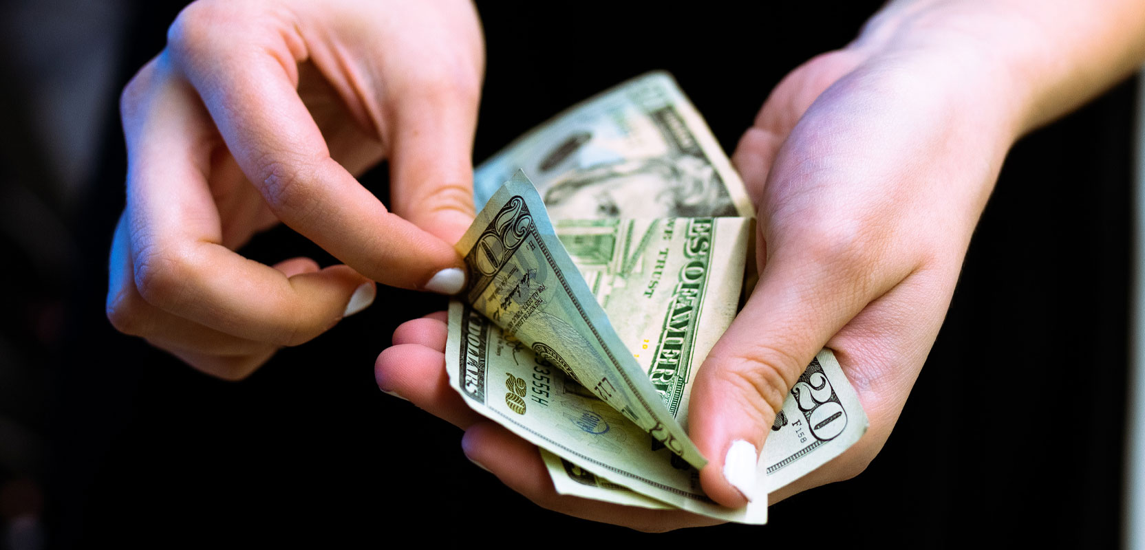 Closeup of a woman holding several twenty-dollar bills