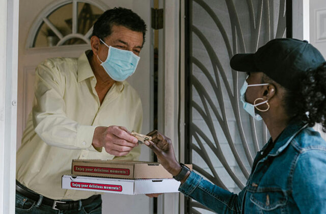 Uber Eats driver handing an order to a customer.