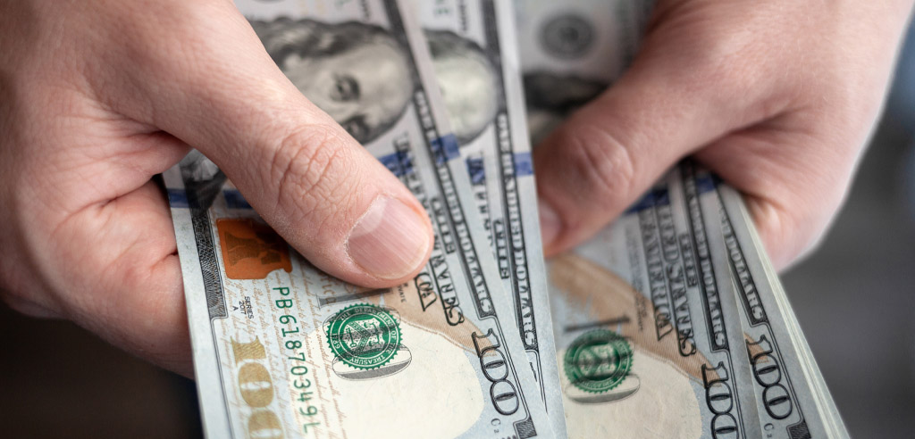 Close view of two hands holding hundred dollar bills