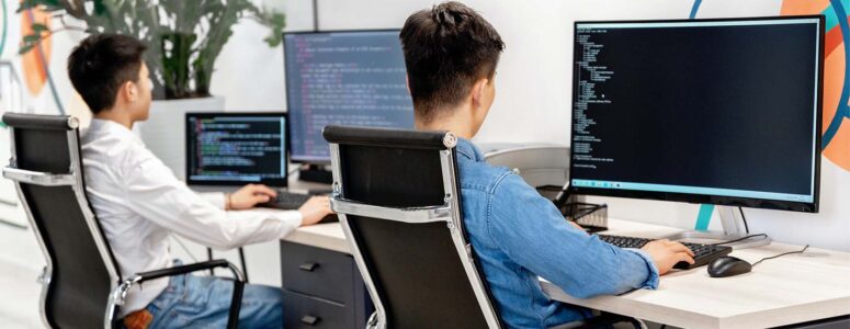 Two web designers sitting in front of large computer monitors