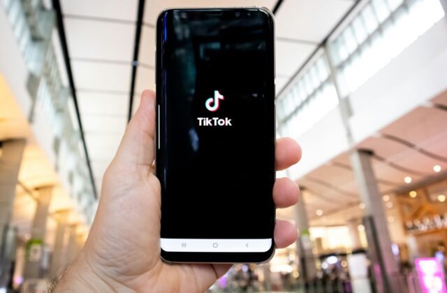 Mobile phone open to the TikTok app, held out in the hand of a TikToker