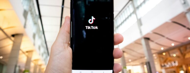 Mobile phone open to the TikTok app, held out in the hand of a TikToker