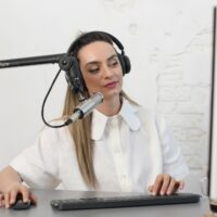Professional content creator wearing headphones and sitting at a desk with a keyboard, mouse, and microphone