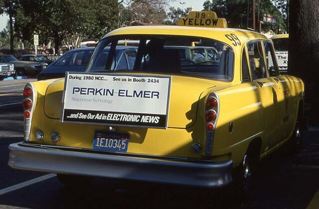 Old-fashioned yellow taxi on a street with an advertisement pasted on the back of the car