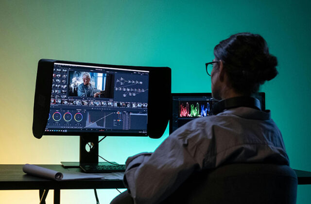 YouTube creator in front of a monitor displaying the interface of video editing software