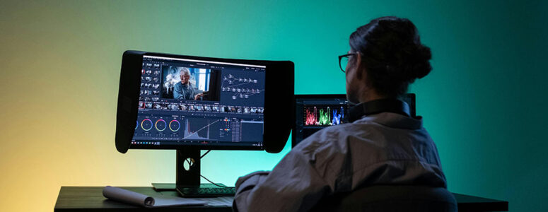 YouTube creator in front of a monitor displaying the interface of video editing software