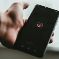 Close view of someone holding a phone displaying the Instagram icon.