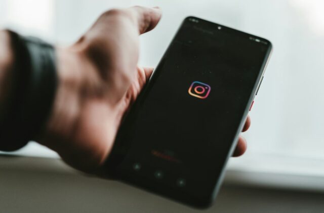 Close view of someone holding a phone displaying the Instagram icon.