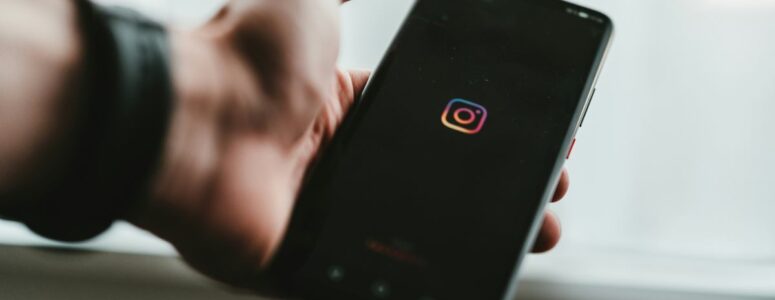 Close view of someone holding a phone displaying the Instagram icon.