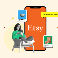 Woman sitting on a chair next to a phone showing the Etsy app, surrounded by various listings