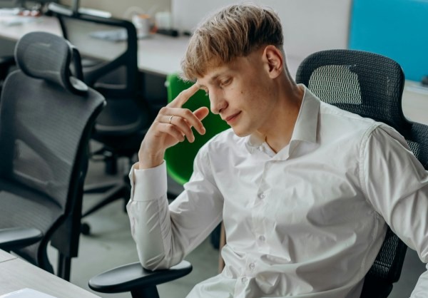 A frustrated hybrid worker sits in an empty office while co-workers are at home.
