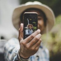 View of an influencer through the lens of a smartphone, which they're holding up to record a social media post