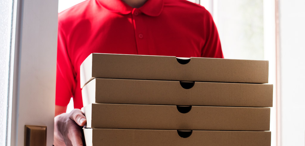 Delivery worker holding a stack of pizza boxes