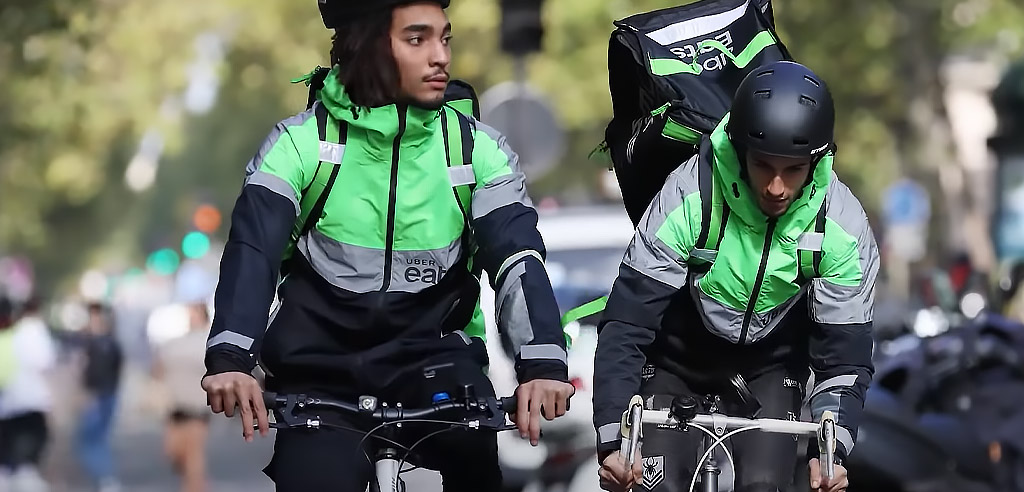 Two Uber Eats drivers on bikes working on their food delivery side hustle