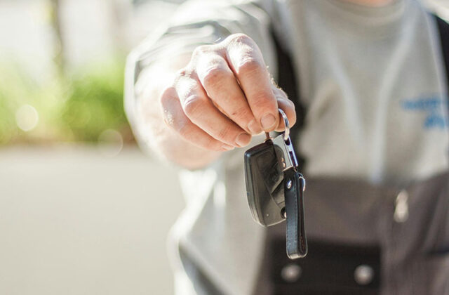 Man handing off keys to a rental car.