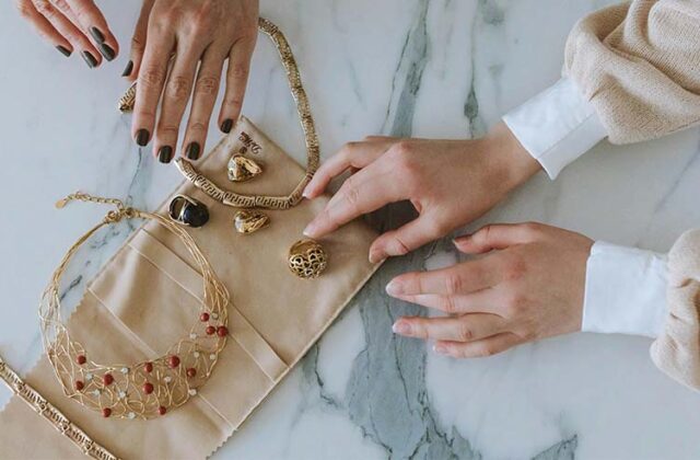 Jewelry seller showing a potential buyer a range of gold rings and necklaces