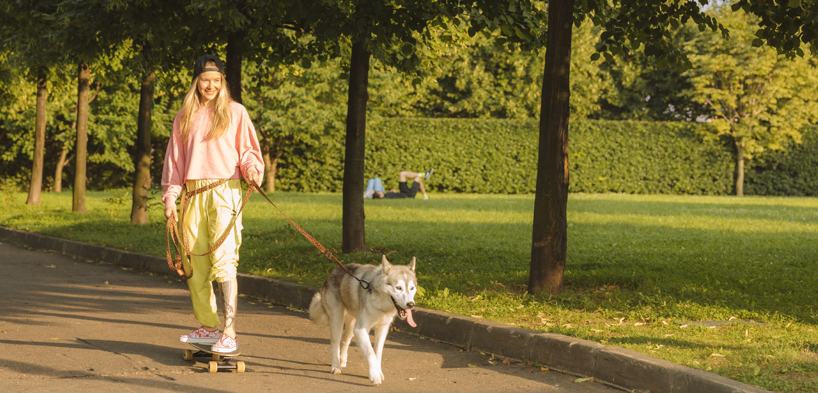 Girl on a skateboard walking a dog on a leash