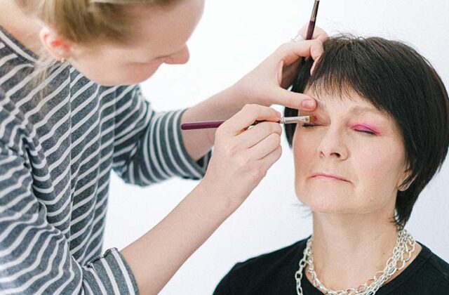 Professional makeup artist applying pink eye shadow to a client